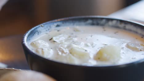 close-up of spoon serving steaming cullen skink soup with potatoes and leeks in cozy lighting