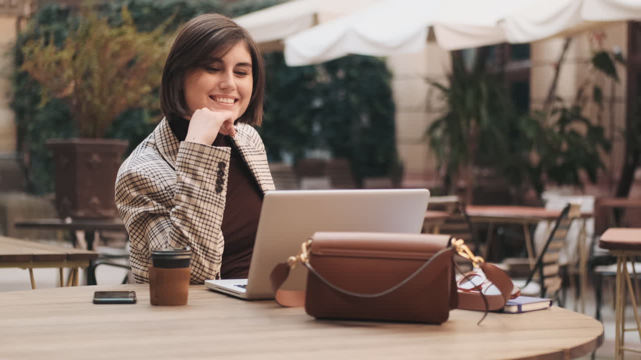 mujer de negocios trabajando en una computadora portátil en un café al aire libre.