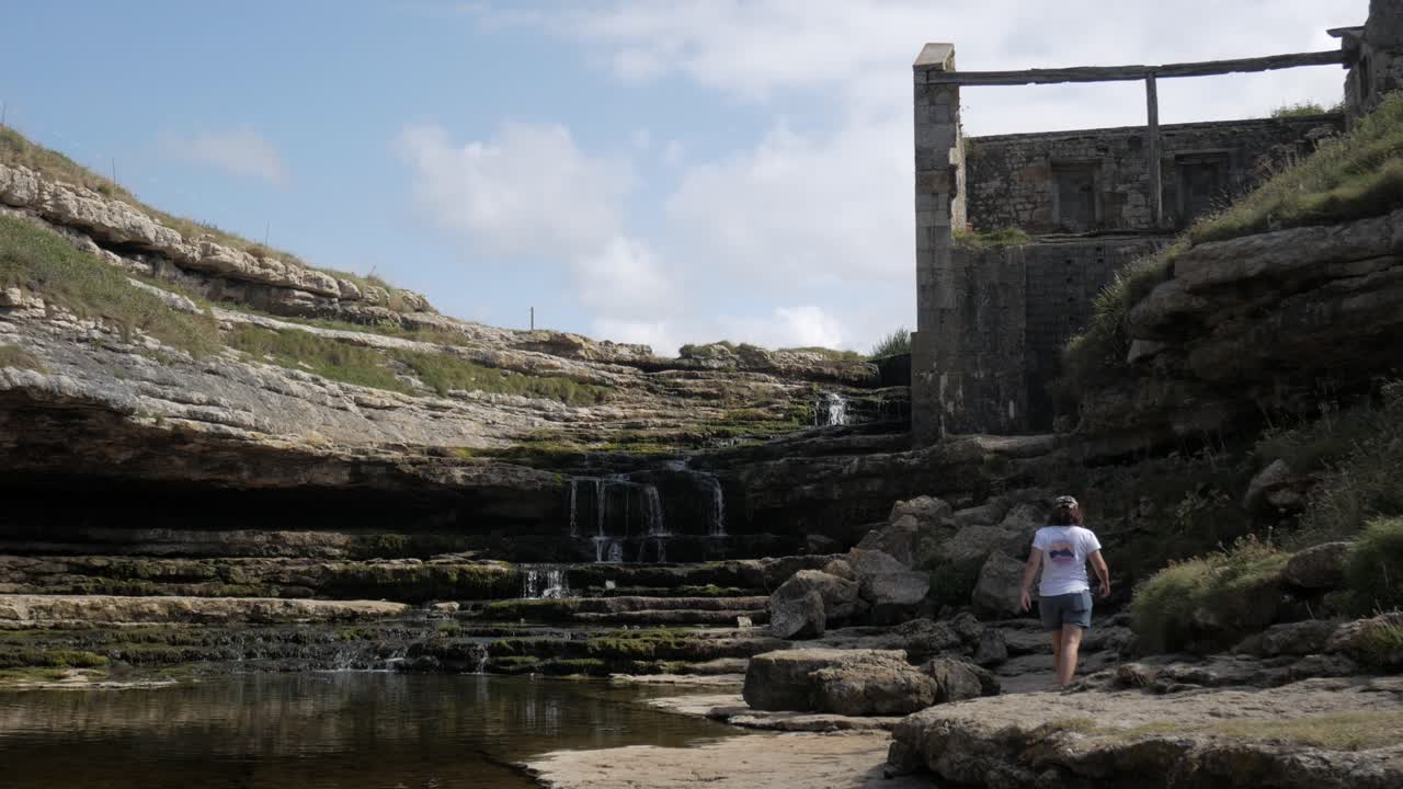 Tranquil riverside scene with small group gathered beneath cliffside, nature in Cantabria