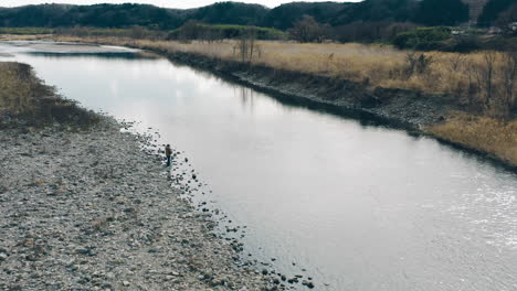 man stand on rocks while fishing in the river at daytime in tokyo, japan