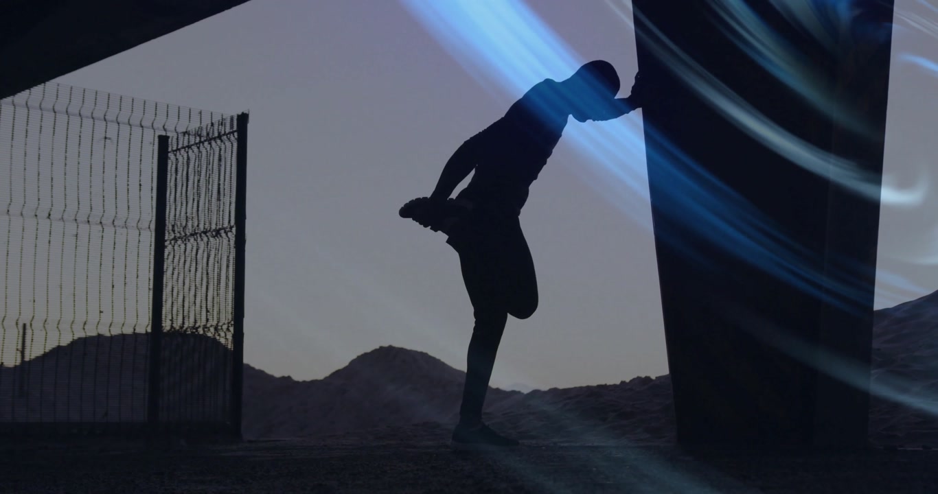 Athlete pushing metal wall at dawn for fitness and transitioning into quad stretch by desert hills