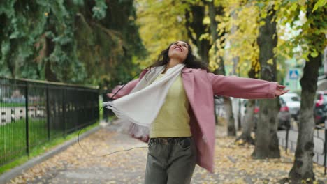 carefree woman listening to music and turning around in city