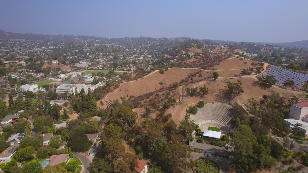 sobrevuelo del campus de la universidad occidental y el vecindario de eagle rock y hacia el auditorio, los paneles solares y el sendero en la cima de la colina en los ángeles, california en un hermoso día de verano