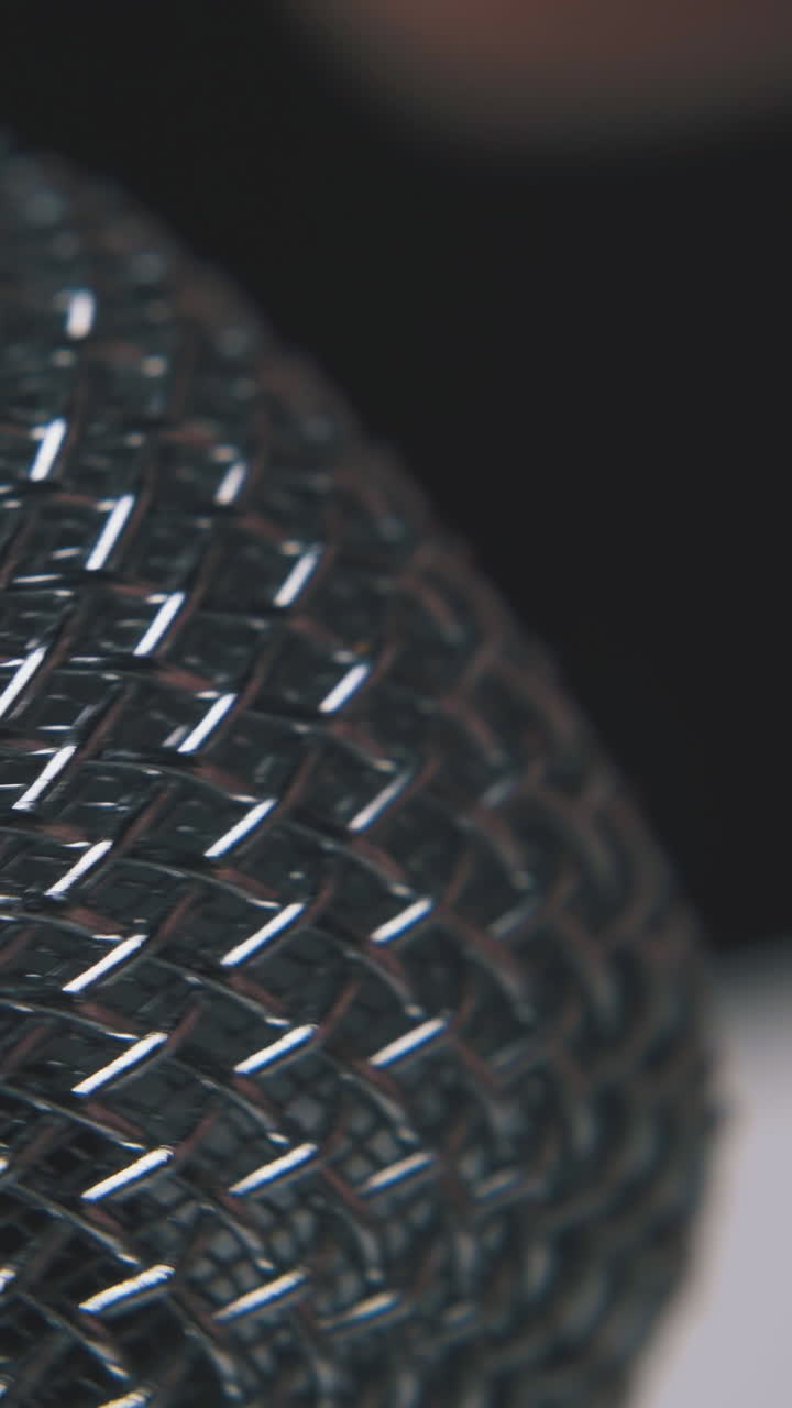 man taps on modern shining metallic microphone by finger on dark background extreme close view
