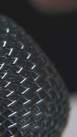 man taps on modern shining metallic microphone by finger on dark background extreme close view