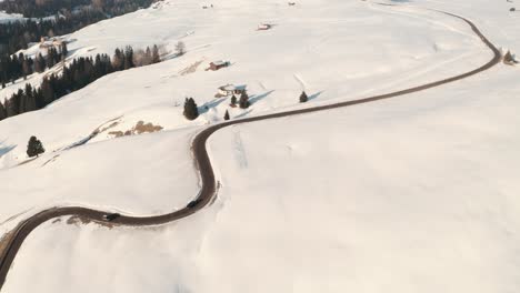 Dolly-back-drone-shot-over-snowy-mountain-road