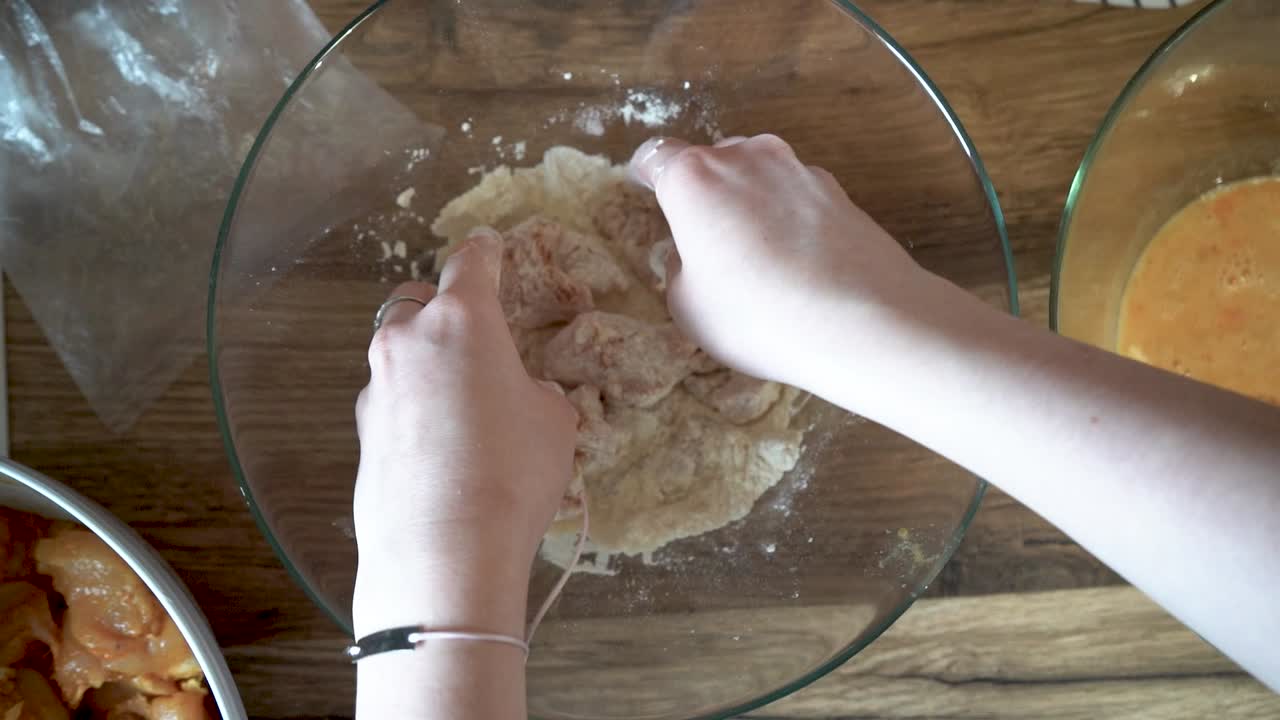 Woman Meat Breading Chicken Breast on a Kitchen Counter