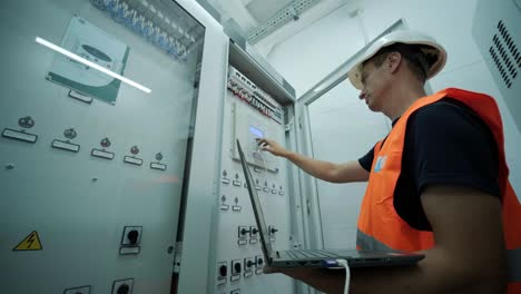 electrical engineer working check the electric current voltage and overload at front of load center cabinet or consumer unit for maintenance in main power distribution system room.