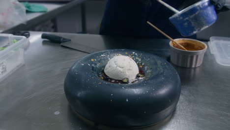 male cook splashes decor on ice cream dessert