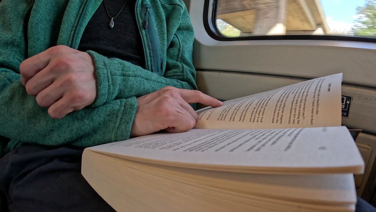 Video of person reading on a moving train (side).