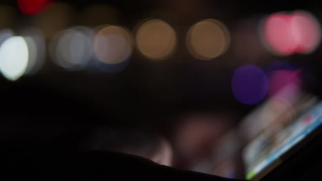 persona usando un dispositivo de tableta digital por la noche con luces de la ciudad en el fondo - fuera de enfoque imágenes de concepto borrosas