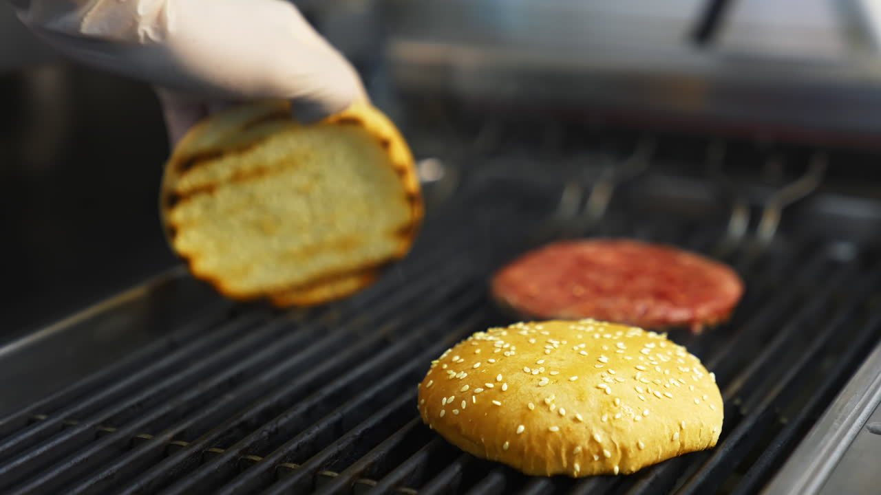 Cooking burgers at restaurant. Close up of chief cooking tasty burger at restaurant