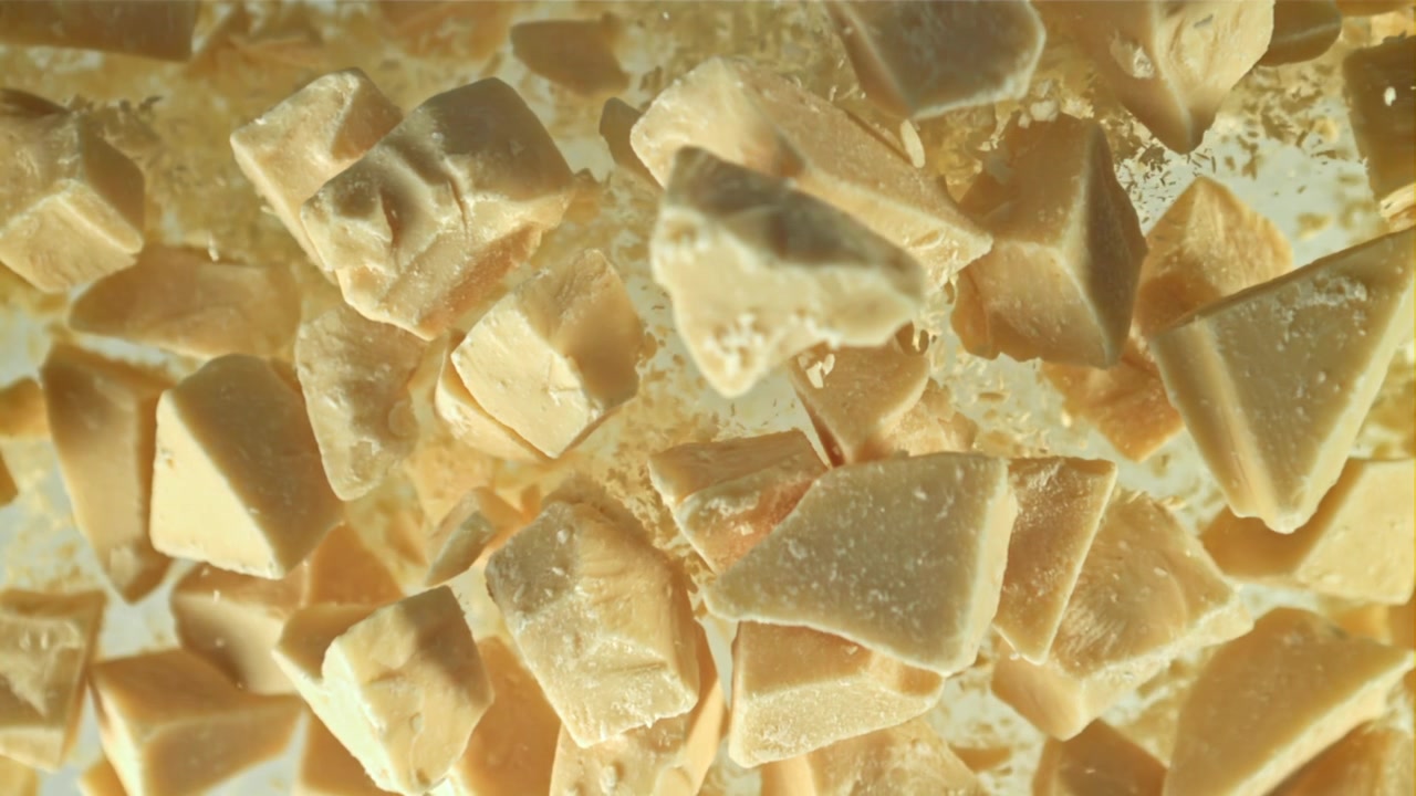 Hvide chokoladestykker og pulver falder i slow motion.