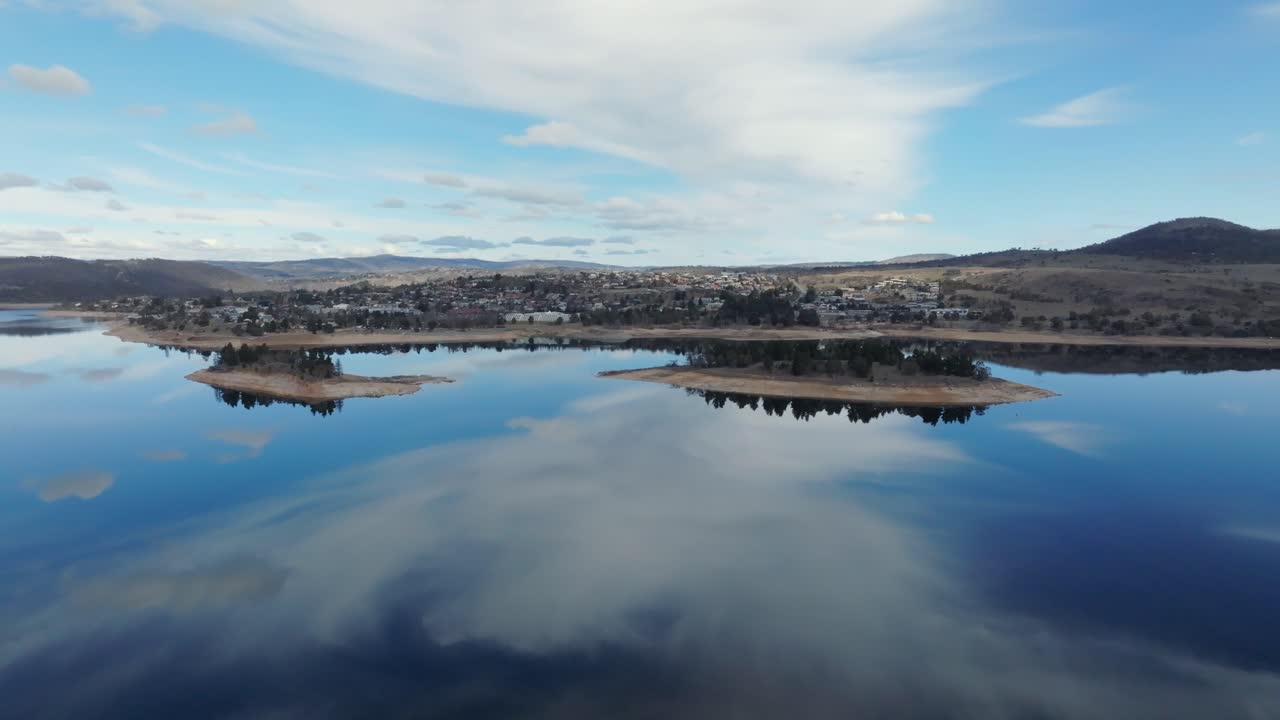 Aerial: shot slowly pulling away from Jindabyne town over the lake on a blue sunny day, NSW Australia