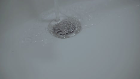 Closeup-of-Running-Water-pouring-into-sink-drain-cover