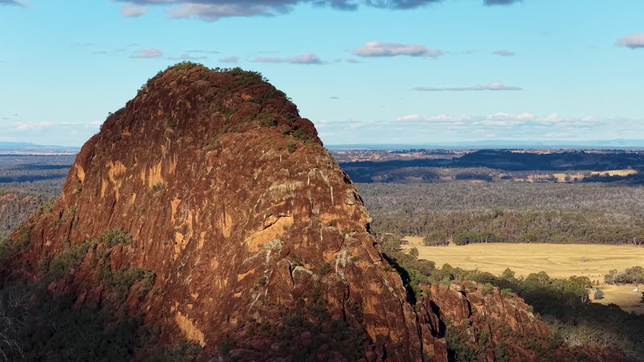 Drone camera smoothly pans Timor Rock, revealing rugged volcanic outcrop and vast Australian landscape