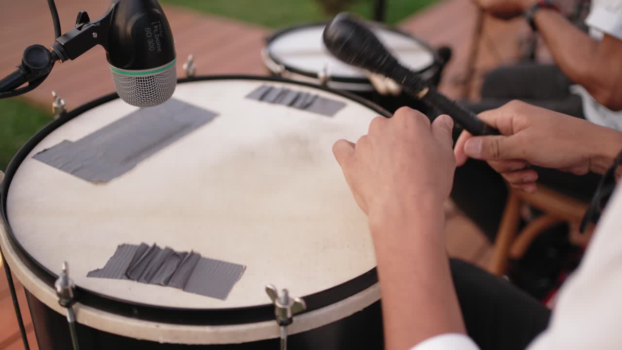 Musician playing hand drum with mic setup outdoors in natural light
