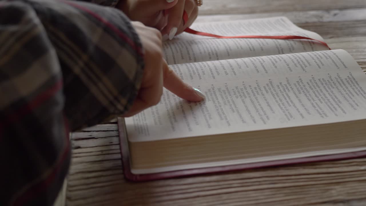 Close up female hands reading bible studying religious scripture at home desk