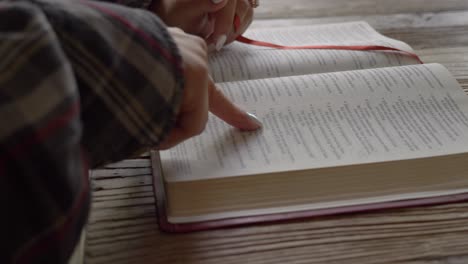 Close-up-female-hands-reading-bible-studying-religious-scripture-at-home-desk