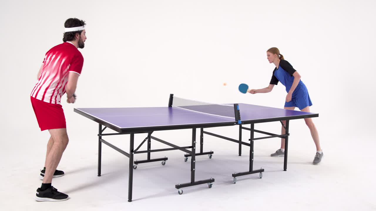 Playing table tennis, man and woman competing in intense match indoors