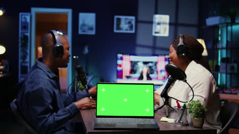 Green-screen-laptop-in-front-of-show-host-recording-podcast,-using-analog-mixer-in-studio