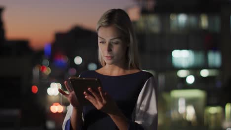Video-of-thoughtful-caucasian-businesswoman-using-tablet-at-night-in-office
