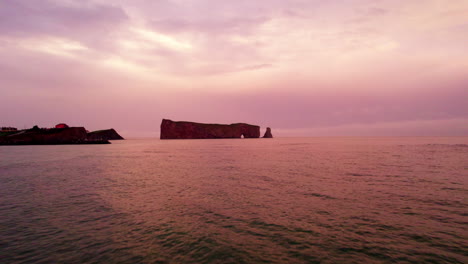 Vista-De-Drones-Alejándose-De-La-Roca-Percé-En-Gaspésie-Durante-Una-Puesta-De-Sol-Nublada