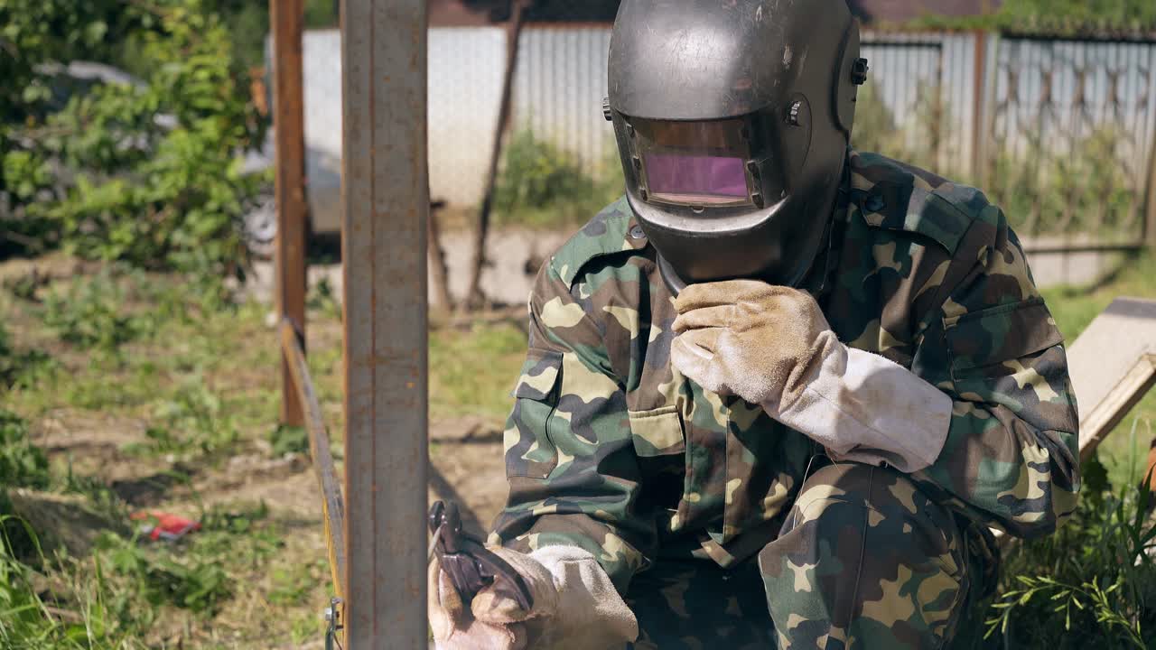 artesano de cámara lenta suelda la valla de la casa de campo en el patio