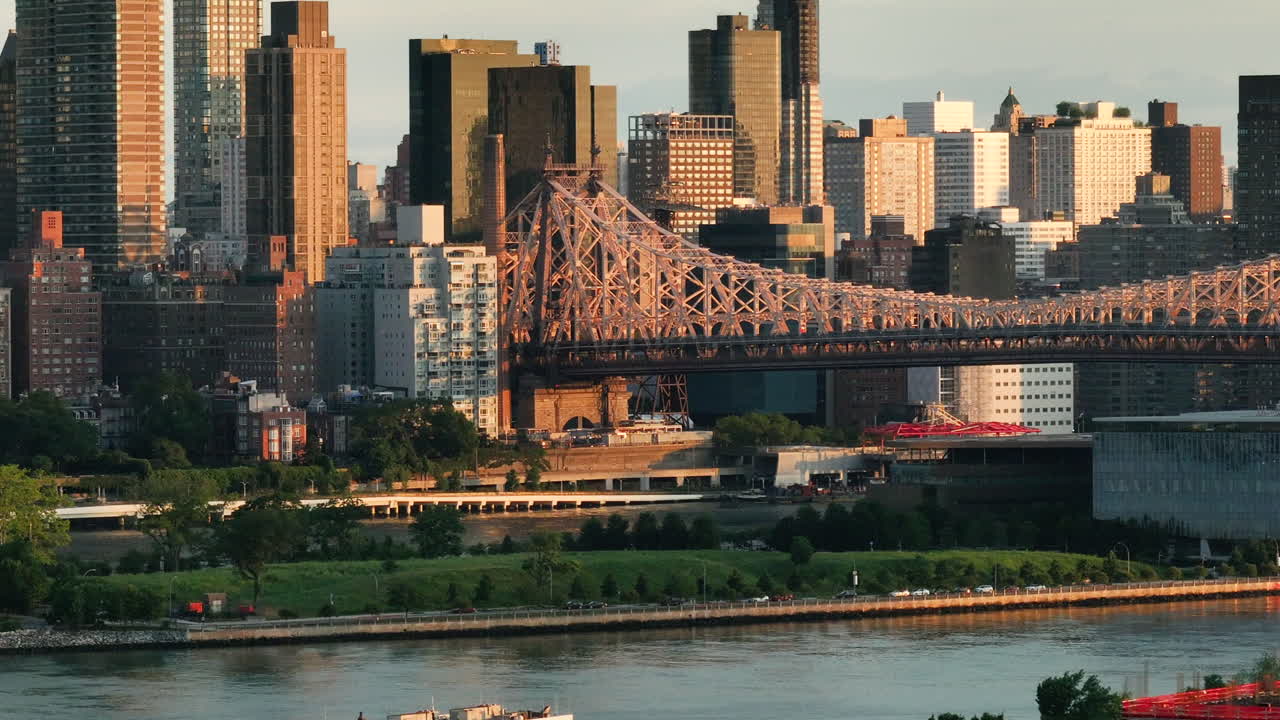 Aerial view of the Queensboro Bridge at sunrise. Shot along the East River with Roosevelt Island and Manhattan in the background