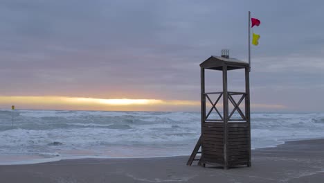 El-Sol-Comienza-A-Brillar-A-Través-De-Las-Nubes-En-Una-Playa-Vacía-Con-Torre-De-Salvavidas-Al-Atardecer