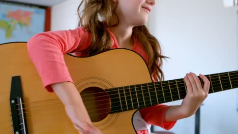 mid section of caucasian schoolgirl sitting on desk and playing guitar in a classroom 4k