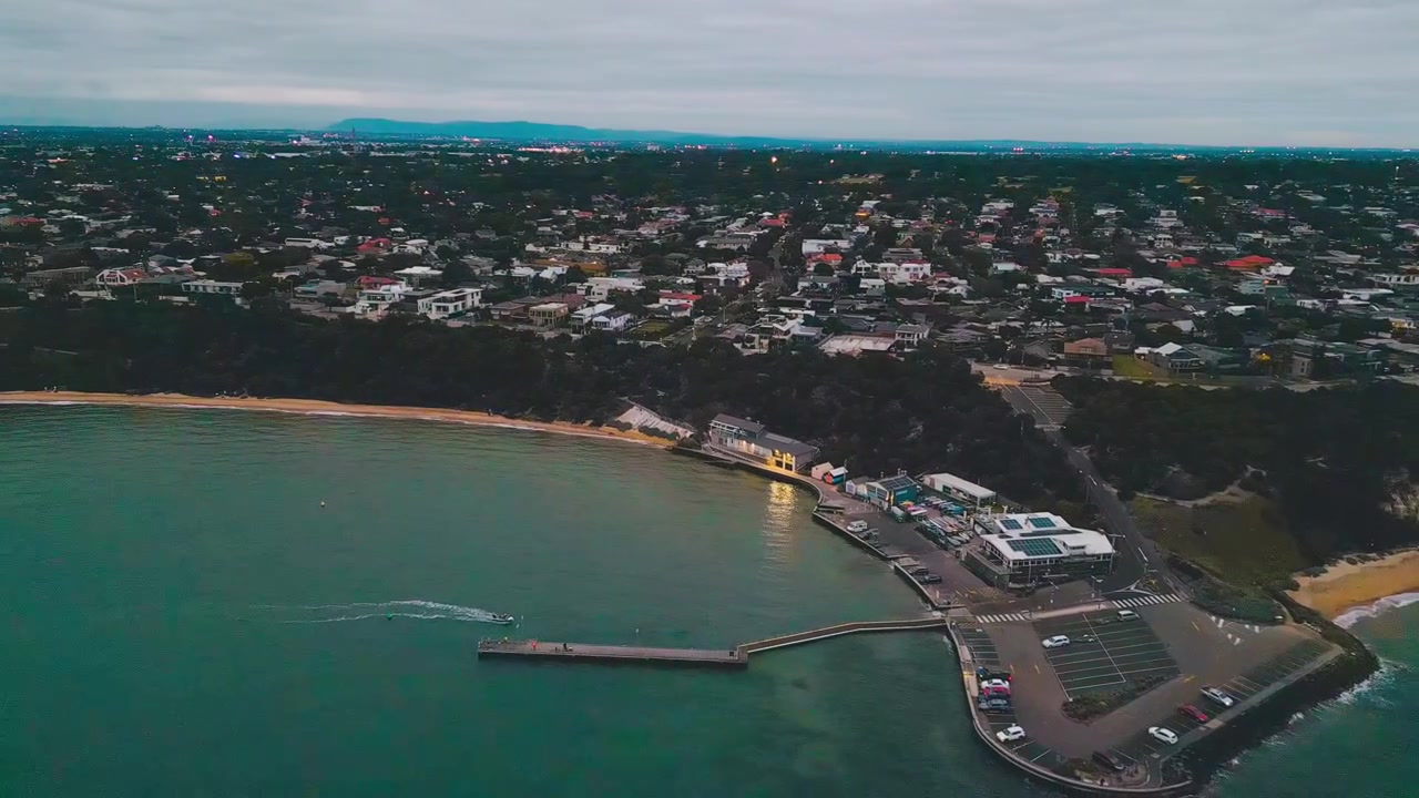 Riprese cinematografiche 4K con drone, panoramica orizzontale per catturare la spiaggia di Half Moon Bay, le calme acque del mare e lo storico relitto della HMVS Cerberus sotto cieli sereni serali