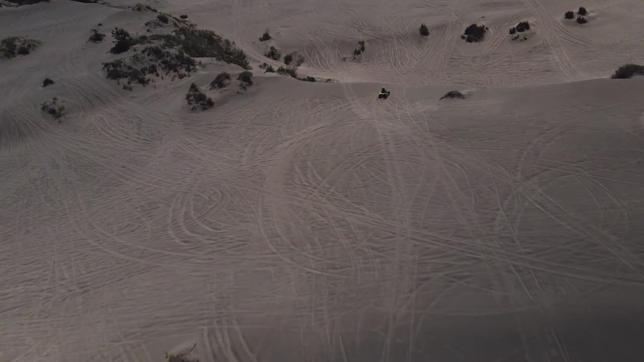 Aerial view following a motorcycle guy in the Ritoque dunes on a sunny day