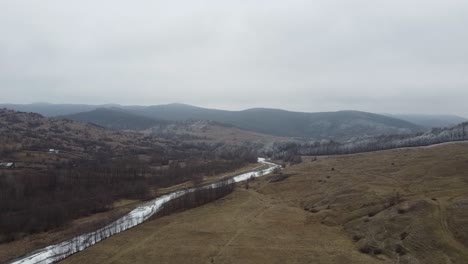 Drone-shot-of-the-forest-and-a-country-icy-river-in-the-late-autumn