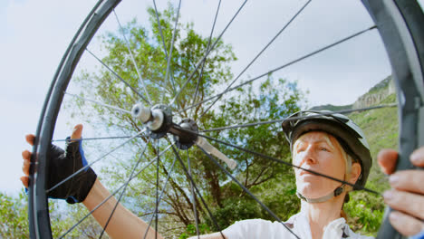 Senior-cyclist-repairing-bicycle-at-countryside-4k