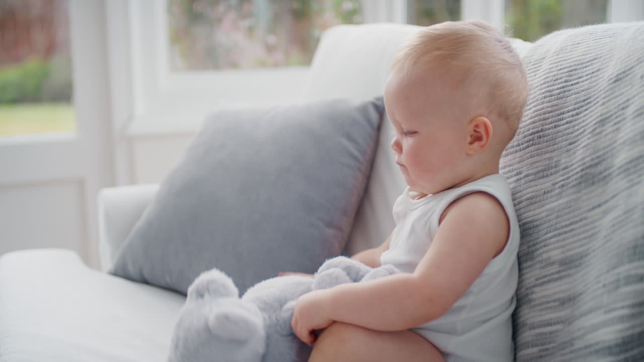 웃긴 아기가 집에서 테디 베어 장난감을 가지고 놀고 행복한 유아가 재미있게 어린 시절을 즐기고 있습니다.