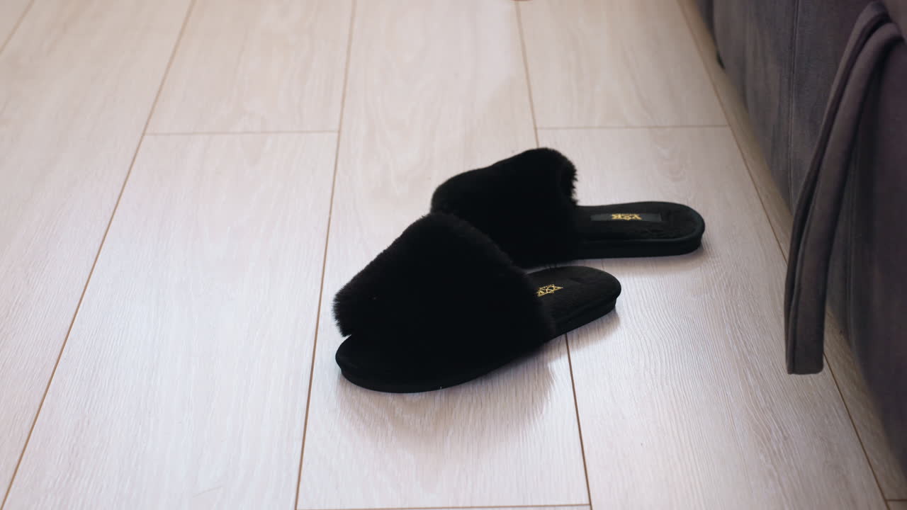 Damesslippers Ochtend, Ontspannen vrouw die in alle rust in haar slippers glijdt, Ochtendscène van vrouw in kleding die in haar slippers glijdt, Vrouw in gestreepte kleding die zachtjes haar slippers aantrekt op een houten vloer bij zonsopgang
