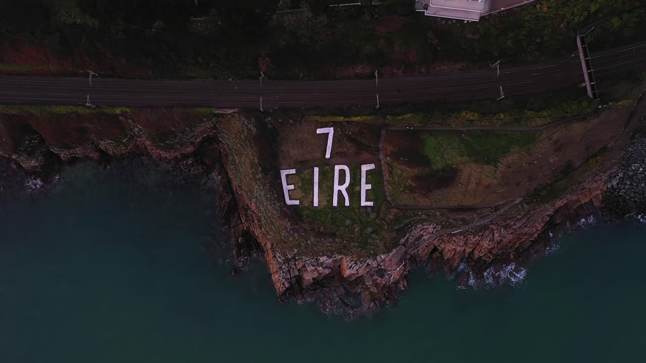 Tanda Penanda Pengawasan Pesisir Perang Dunia II Eire 7, Killiney, Dublin, Irlandia. Januari 2020. Drone naik secara bertahap memperlihatkan rumah-rumah pinggir kota dan tebing pantai.