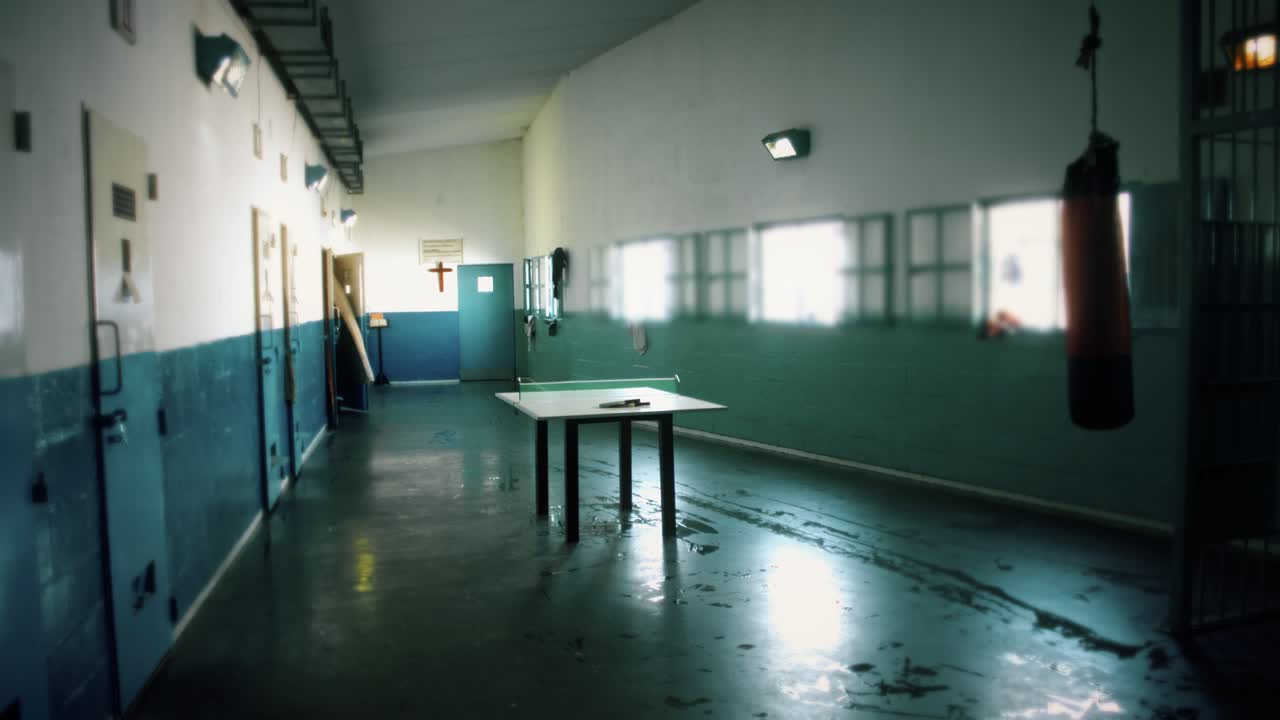 Düsterer, leerer Gefängniskorridor mit Zellentüren und Boxsack.
