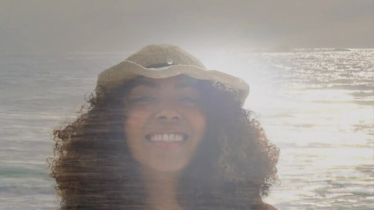 Animation of happy african american woman at beach smiling, over sea