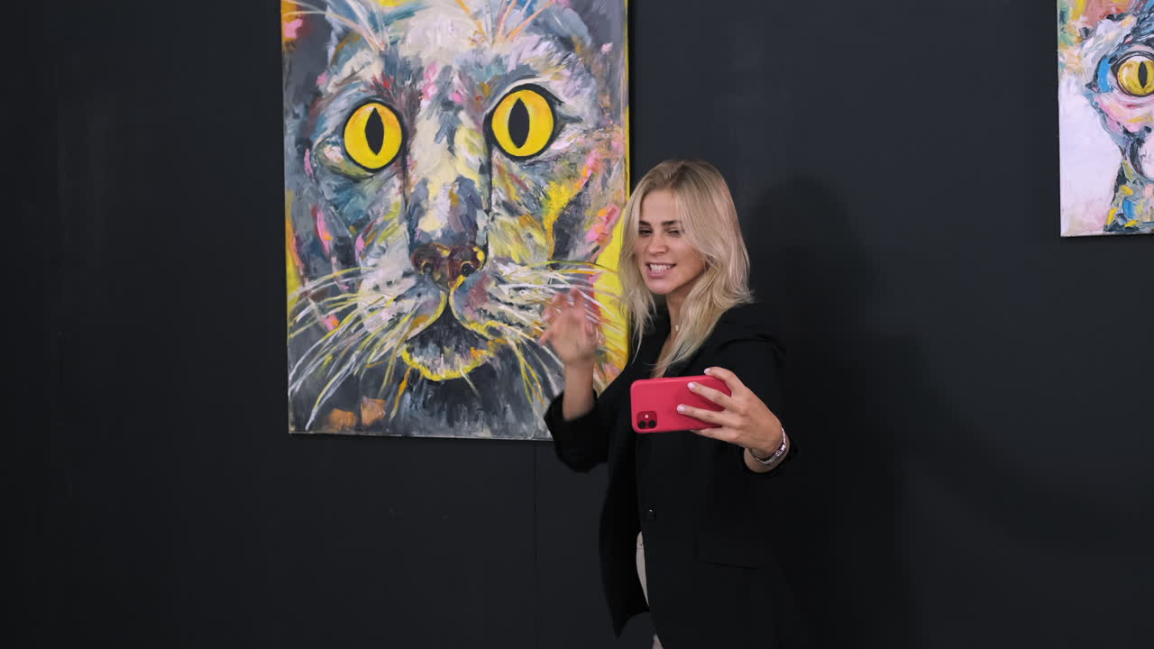 추상적인 고양이 그림 앞에서 셀피를 찍는 여자