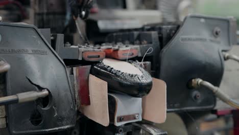 proceso de conformación y clavado de zapatos utilizando una máquina industrial en una fábrica