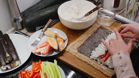 woman making japanese sushi rolls at home, close up