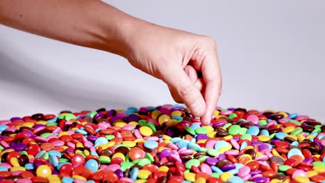 hand selecting candies from a vibrant pile