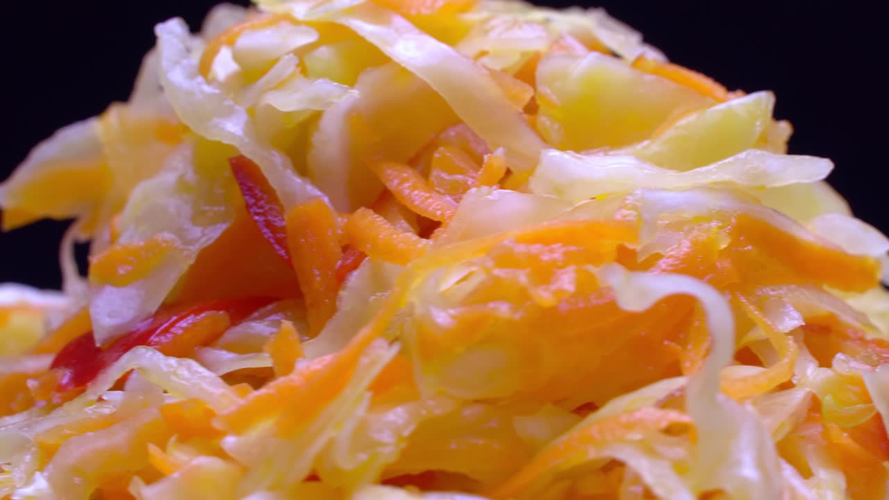 ensalada de verduras frescas en un plato blanco gira sobre un fondo negro.