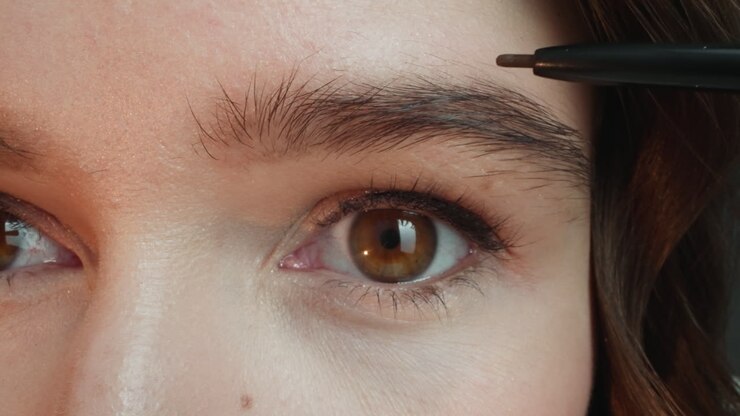 Young woman draws contour for eyebrows with dark pencil