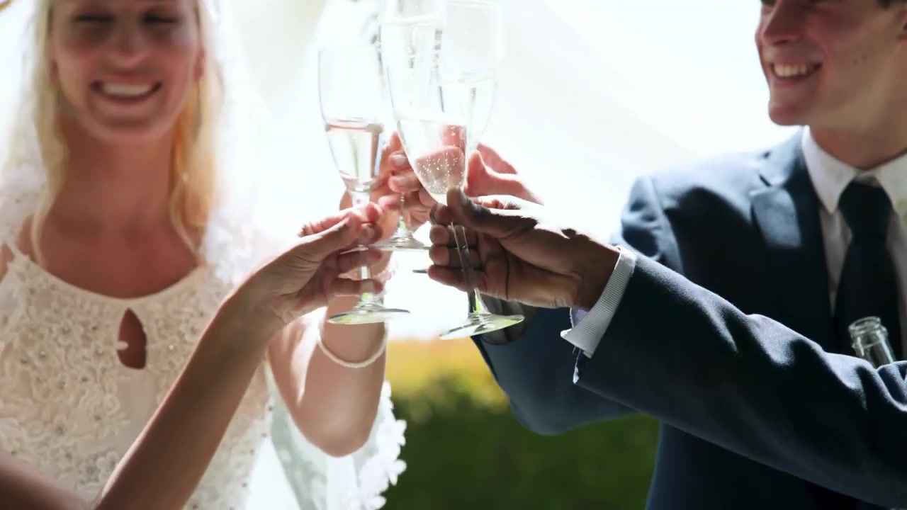 Guest pouring bubbly, wedding couple clinking flutes and sipping, gold confetti falling, camera up