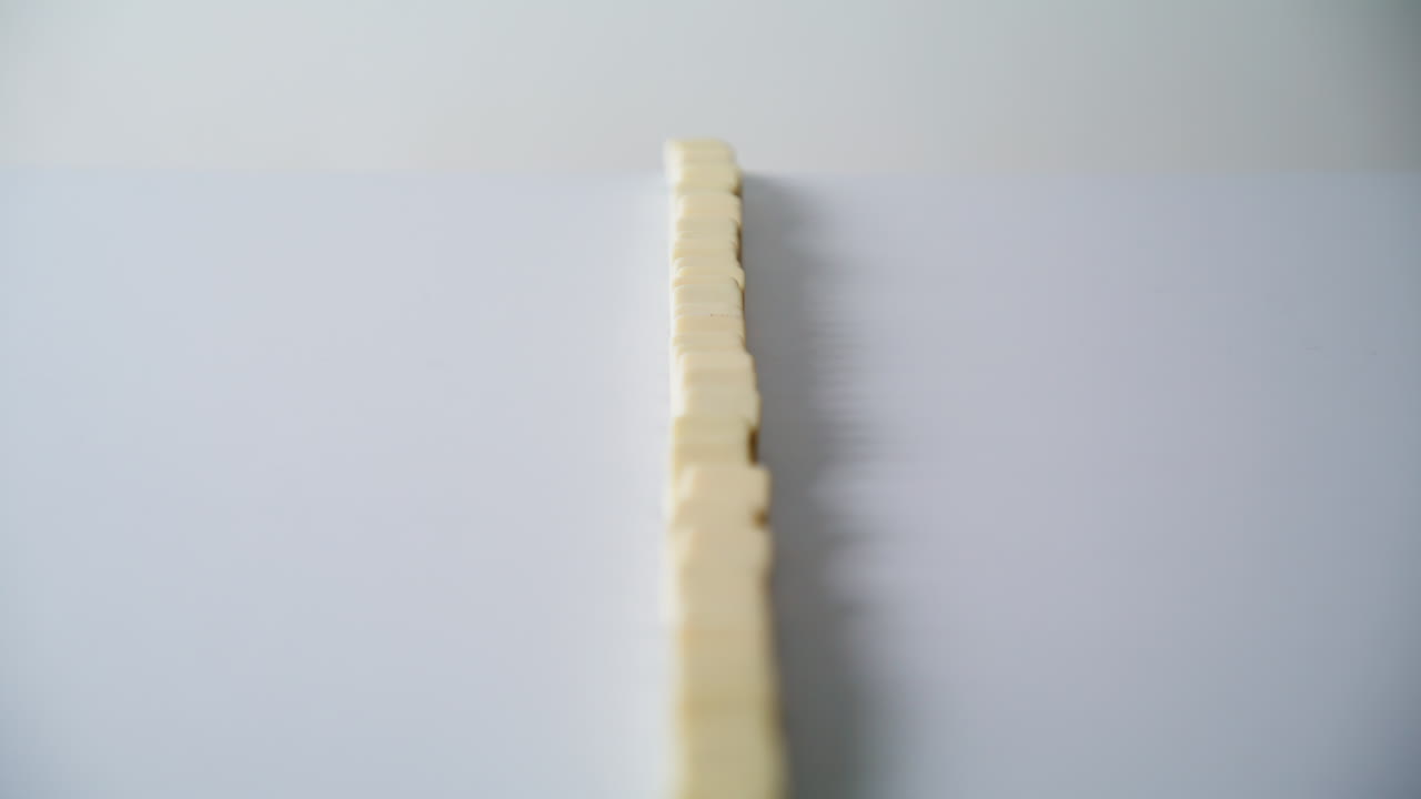 Hand destroying domino row on surface closeup. Unrecognizable man pushing blocks