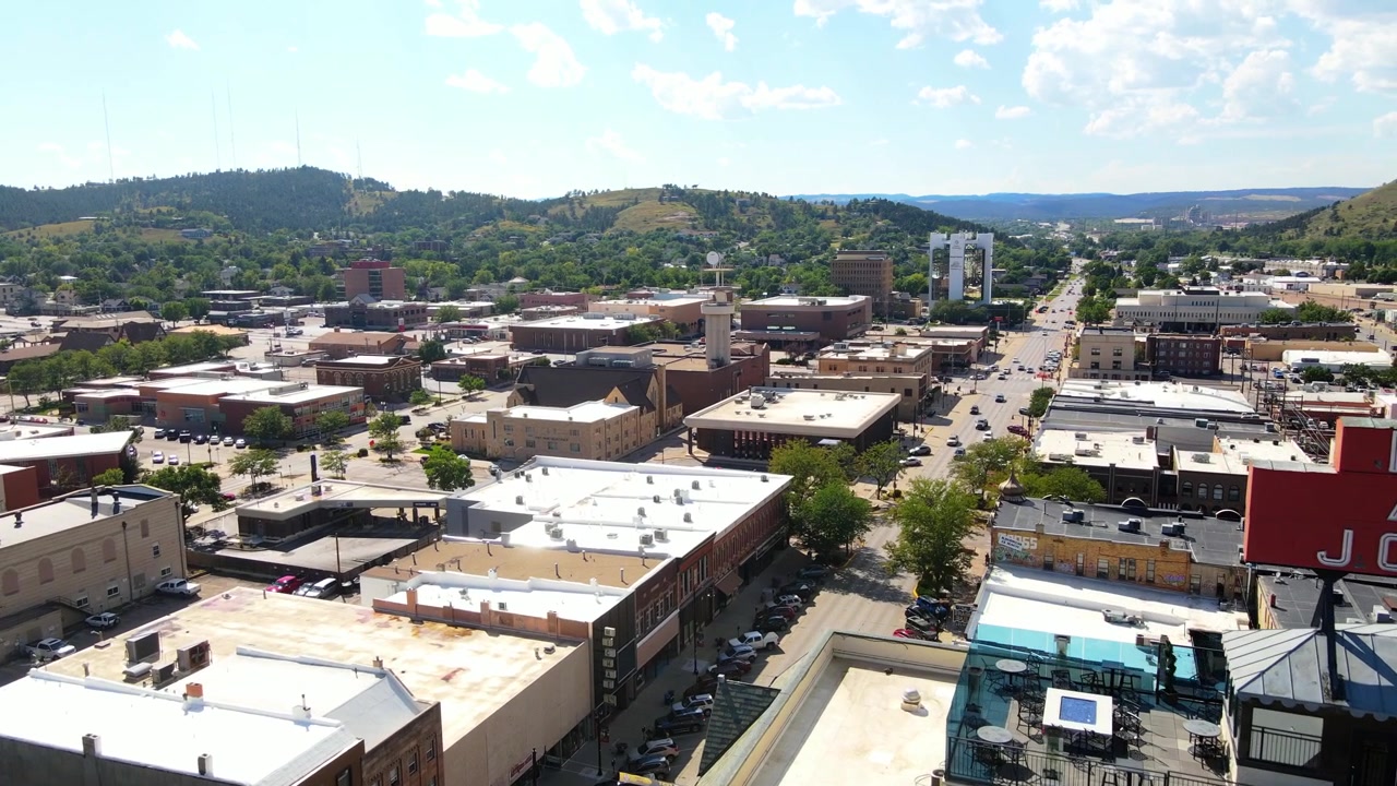 Aerial drone flying past the Hotel Alex Johnson sign revealing more of downtown Rapid City, South Dakota