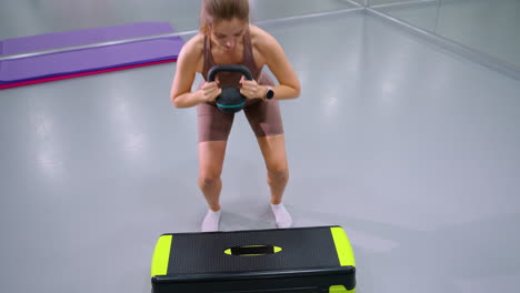 top-down view of fit woman performing strength training exercise lifting weight in modern gym, large mirror and yoga mat in background highlight workout intensity and focused fitness routine